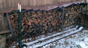 A stack of firewood covered with a Homemade Strapless Firewood Tarp.