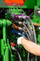 Back end of a John Deere tractor with Color-Coded Hydraulic Hose Couplers and a person's left gloved hand changing a line