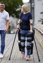 A man & woman walking toward the camera with the woman wearing a Lifeward ReWalk Mobility Exoskeleton.