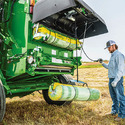Man using a Round Baler Net-Wrap Lifter mounted on a farm implement in a field